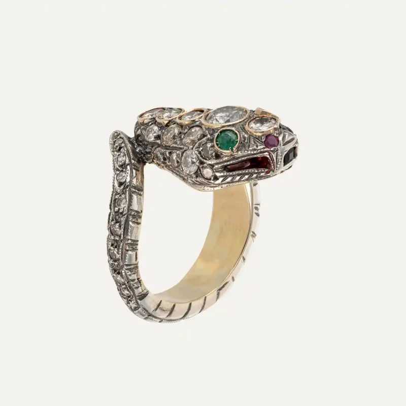 Side view of a snake ring in silver and gold with diamonds and precious stones.